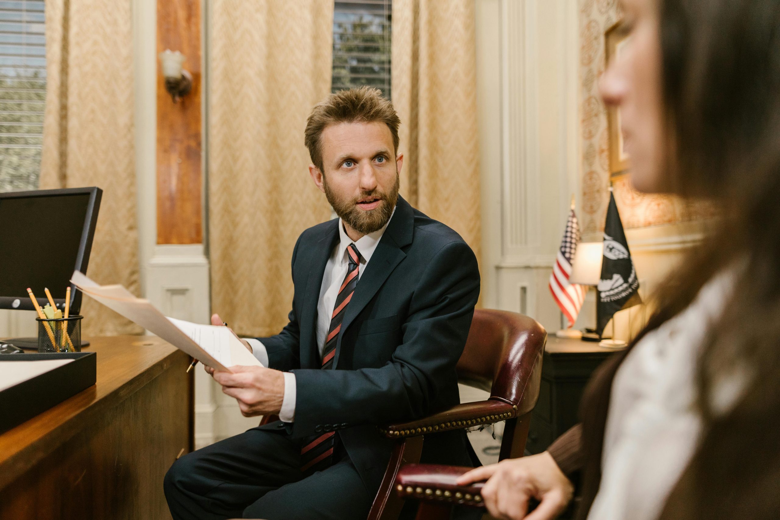 A Man in Business Suit Holding a White Paper While Sitting on the Grown Chair